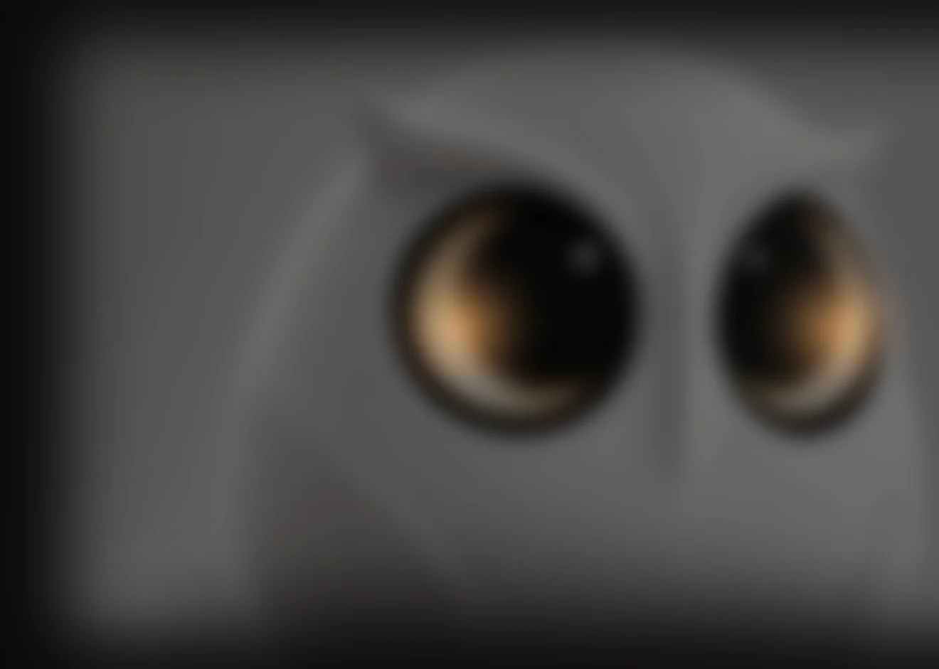 暗色中的未来 Owl 桌面硬件方向：只能看到完整的模糊体量与两块圆形眼屏的暖光，表面结构不可辨